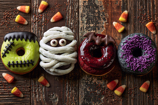 Overhead view of a row of Halloween monster donuts on a distressed dark table