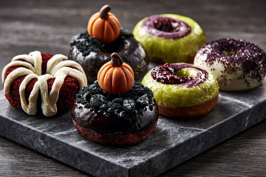 Elegant display of diverse Halloween donut flavor varieties arranged on a dark marble slab