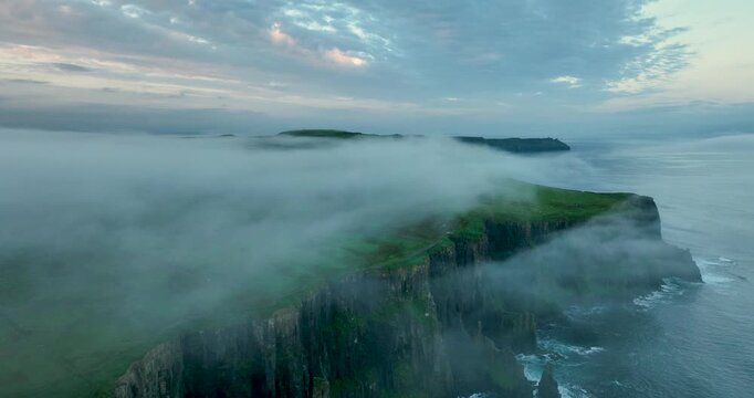 Aerial drone flight above Cliffs of Moher with low clouds drifting over sea cliffs, Ireland