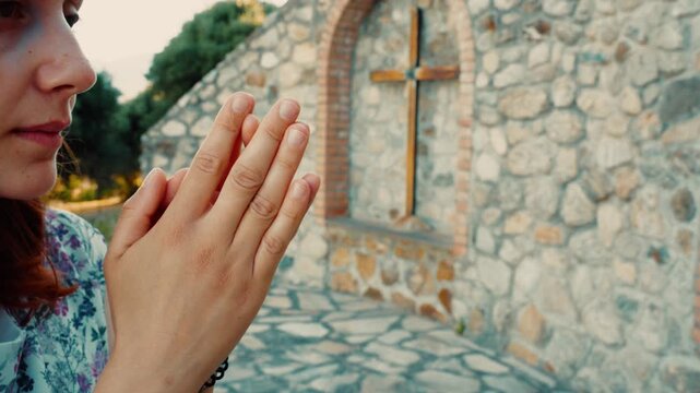 Woman prays for God forgiveness at an outdoor Calvary with religious crucifixes