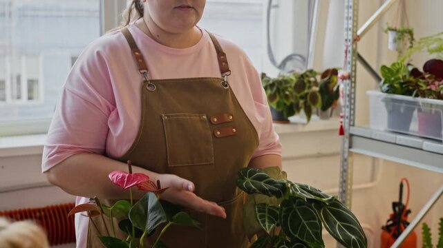Portrait of Caucasian woman wearing apron, talking and gesturing while explaining plant care. Footage is ideal for small business promotions, floristry tutorials, or educational content