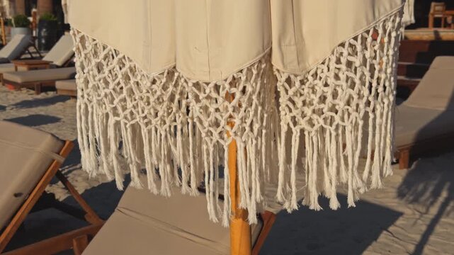 Handcrafted macrame boho umbrella with decorative fringe and knotted weave patterns at a sunny beach pool lounge area