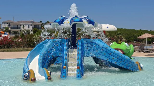 Blue whale shaped kids play structure with mini slides in a shallow pool at an aqua park in Cesme Turkey.