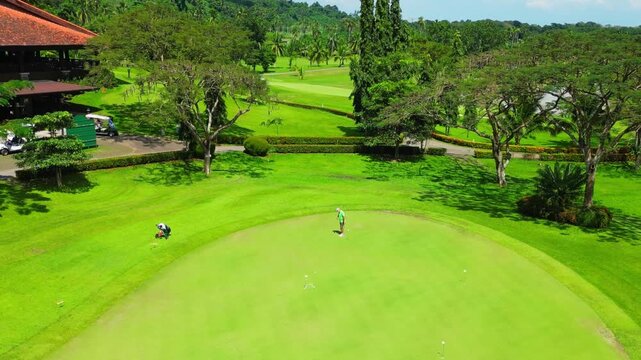 Smooth drone pulldown shot at Canlubang Golf and Country Club golfer preparing for a swing, tropical greenery, palm trees, and expansive championship fairways.