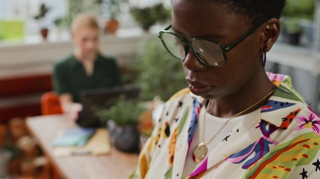 African American young adult woman using tablet computer in creative office. Clip is ideal for technology, digital marketing, and modern workplace commercial campaigns