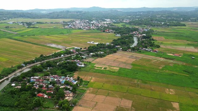 Cinematic forward drone flight following the S-shaped Morong River toward the Morong Solar Parola, revealing rice paddies, residential homes, and distant mountains.