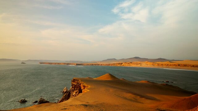 Golden coastal sandstone cliffs with dunes sloping to ocean shoreline in Paracas National Reserve Peru, establishing background with nobody