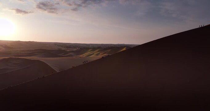 Desert dunes near Huacachina, Peru, with people silhouettes walking along the ridge. Commercial travel, tourism and landscape footage, aerial view