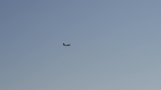 Small passenger plane flying across a clear blue sky. Filmed near Stokmarknes Airport in Hadsel Municipality, Norway, ideal for aviation and travel themes