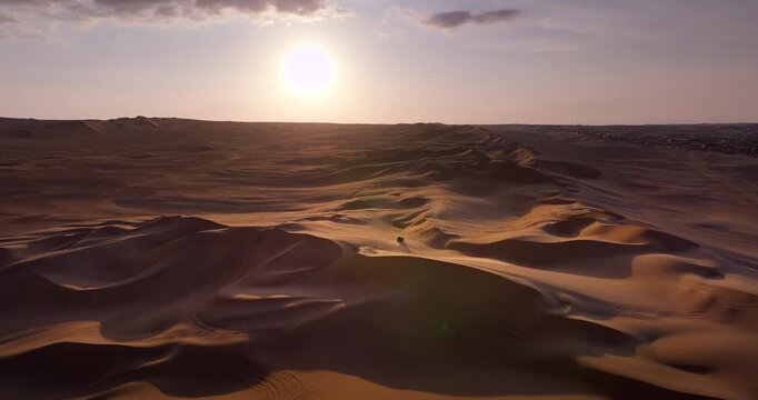 Off-road buggy travelling across the sand dunes near Huacachina, Peru, during sunset, showing an expansive desert landscape and vehicle tracks in the sand, cinematic aerial views