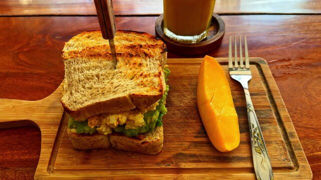 Toasted sandwich with mango slice and coffee on wooden table, close-up.