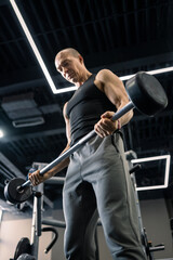Obraz premium Muscular man lifting barbell during strength training in gym