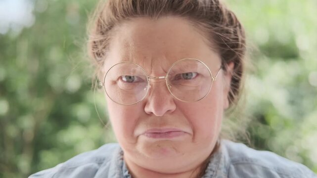 Mature woman wearing eyeglasses looking suspiciously, skeptical facial expression, Recognizing deception, distrust doubt, critical thinking, decision making, human emotions, psychology, close portrait