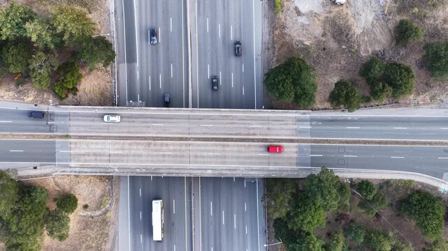 Aerial top down view of a highway overpass and multi lane freeway intersection with driving cars