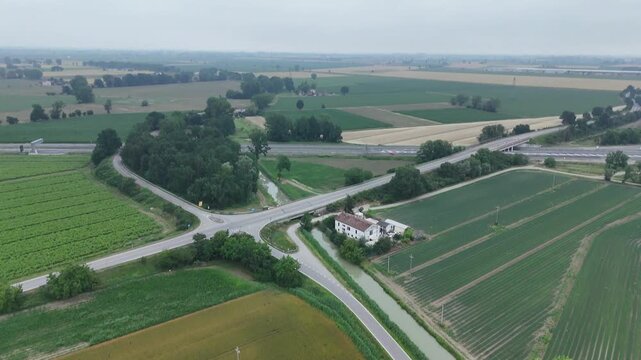 Drone flies above garlic fields, irrigated farmland and rural crossroads near Cascina Secca, San Pedretto, Monticelli d'Ongina, Italy, revealing the intensive agricultural landscape of the Po Valley,