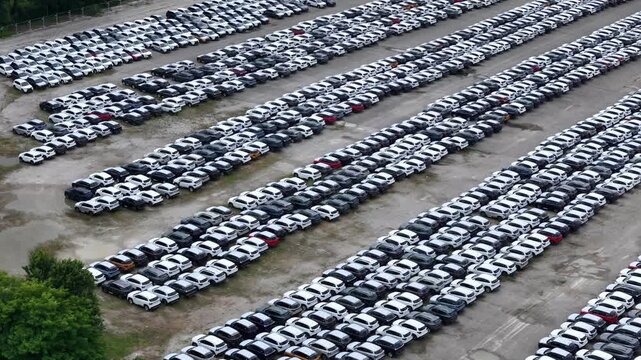 Finished crossover SUVs fill organized storage lanes at a large automotive logistics compound awaiting shipment, wholesale distribution and dealer allocation, slow aerial pan.