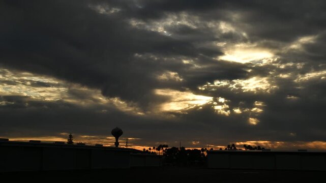 Dramatic time lapse of a glowing sunset beneath dark clouds at Falcon Field Airport in Mesa, Arizona, capturing changing light and atmosphere over a regional aviation setting.