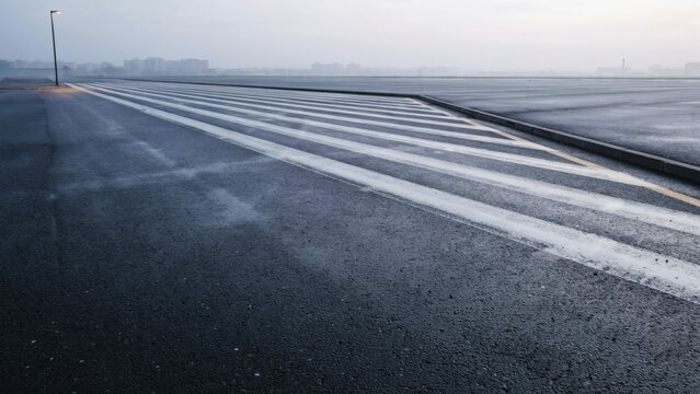 Snowy airport runway with white lines on dark asphalt during winter weather conditions