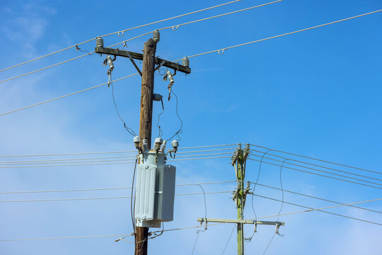 Power lines run along wooden poles against in an urban area
