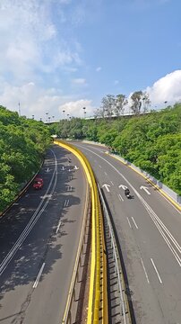 Vertical static shot of winding road through Bosque de Chapultepec with cars passing in Mexico City