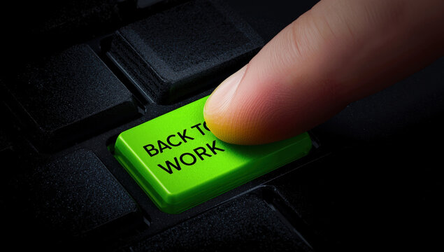 A human finger pressing a bright green computer keyboard key with the text back to work printed on the surface
