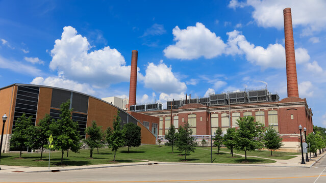 Industrial powerhouse building with tall brick chimney against blue sky