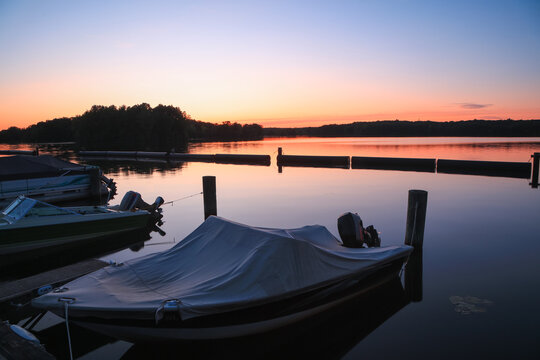 Boats moored at a peaceful lake dock during sunset