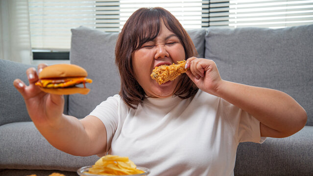 Overweight Asian woman enjoying fast food at home