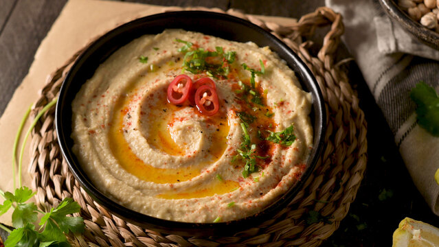 Creamy hummus dip in a bowl topped with olive oil and red chili