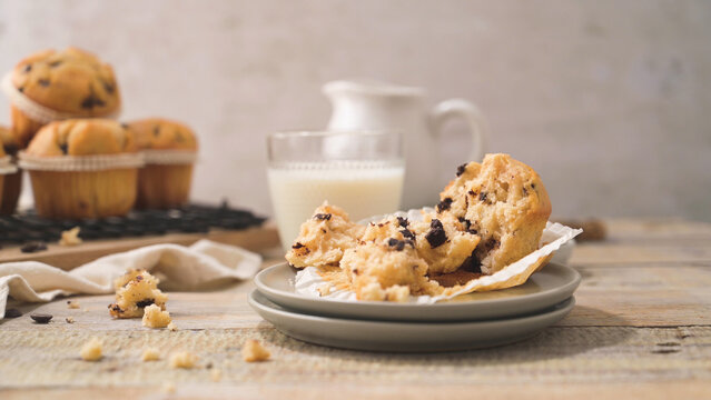 Freshly baked chocolate chip muffin torn open on a rustic wooden table
