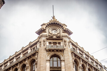 Fototapeta premium White building with neoclassical architecture, clock and sculptures on its facade, 