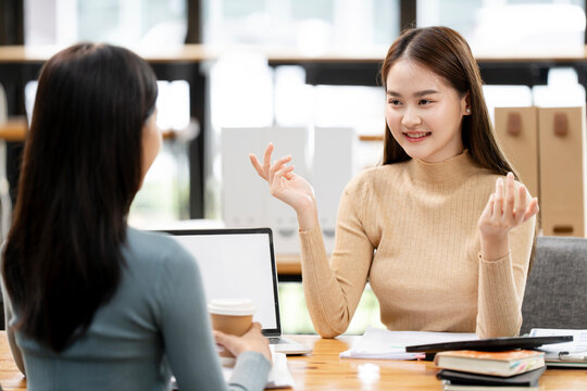 Asian businesswomen discussing work in office.