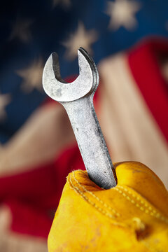 Worn work glove with wrench over the American flag. Symbolic of blue collar workers, USA manufacturing, pride in products Made in United States of America, or celebrate Father's day or US Labor Day.