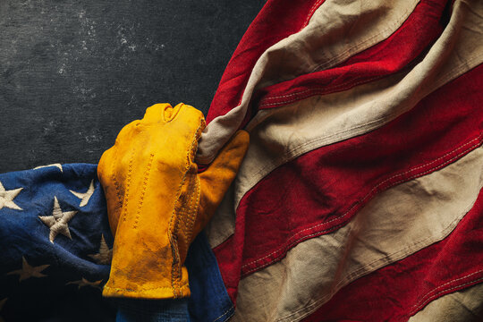 Worn work glove pulling back the American flag. Symbolic of blue collar workers, USA manufacturing, pride in products Made in United States of America, or to celebrate Father's day or US Labor Day.