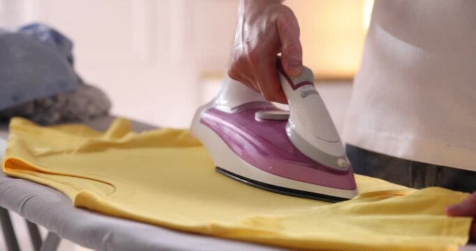 Man ironing t-shirt on board at home, closeup