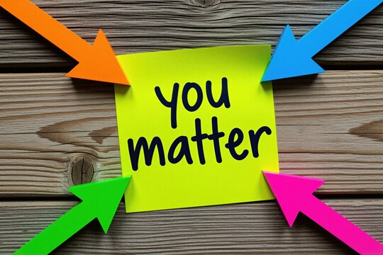 Yellow sticky note with handwritten matter text on wooden surface. Bright colorful arrows point at paper message. Motivation concept for mental health, support. Positive psychology reminder for self