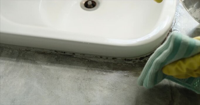 Close up of Asian Woman Hand Spraying Detergent and Wiping Bathroom Sink with Microfiber Cloth, Housekeeping Hygiene Routine