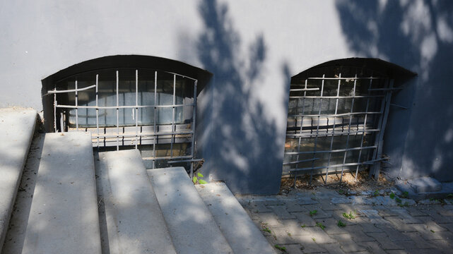 A small window with a grate at ground level in the building, similar to a basement ventilation hole.