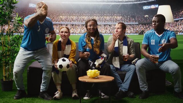 Group of friends follow a soccer game at home as immersive broadcast brings them close to action while football supporters drink beer on the couch.