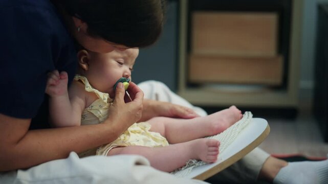 Baby sitting with adult support on a soft indoor mat, wearing a light yellow outfit during a calm caregiving moment