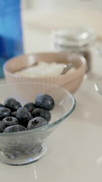 Vertical video: Camera panning bringing bowl, berry bowl into focus on counter showing berries