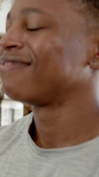 Vertical video: Smiling man in grey tee relaxing then turning head right at home, with stud earring