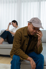 Obraz premium Stressed Asian couple sitting on a sofa after an argument at home. Concept of relationship conflict, marriage problems and mental health. Vertical Shot