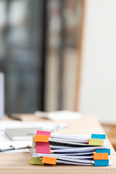 Stack of business documents organized with colorful paper binder clips on office desk.