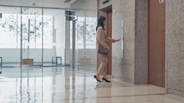 A young professional woman standing near large windows in a bright modern office with natural light and a confident posture.