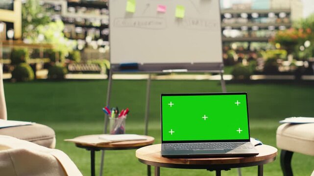 Laptop green screen on table in clean empty rooftop office terrace, editable screen replacement and chroma key mockup, outdoor business environment, urban office, for screen replacement.