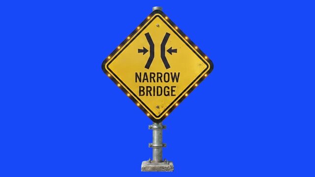 A yellow diamond-shaped road warning sign reading "NARROW BRIDGE" with road narrowing arrows mounted on a pole against a solid blue background.