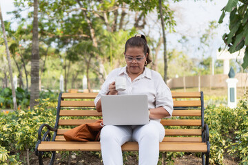 Fototapeta premium Woman working on laptop drinking coffee outdoors