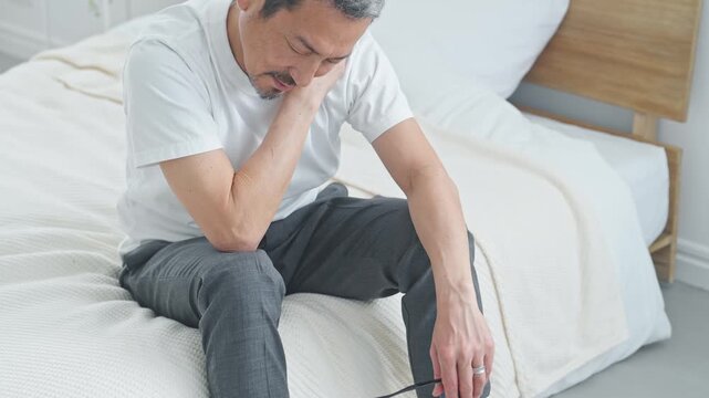 肩こりに悩むシニア男性。疲労、疲れ、ベッド、ミドル、中高年、ストレス、加齢、老化、落ち込む、がっかり