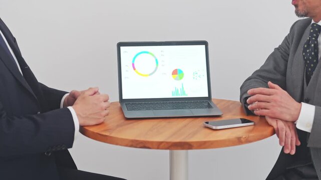 ノートPCを見ながら会話するビジネスパーソン。営業、提案、会議、マーケティング、グラフ、分析、調査